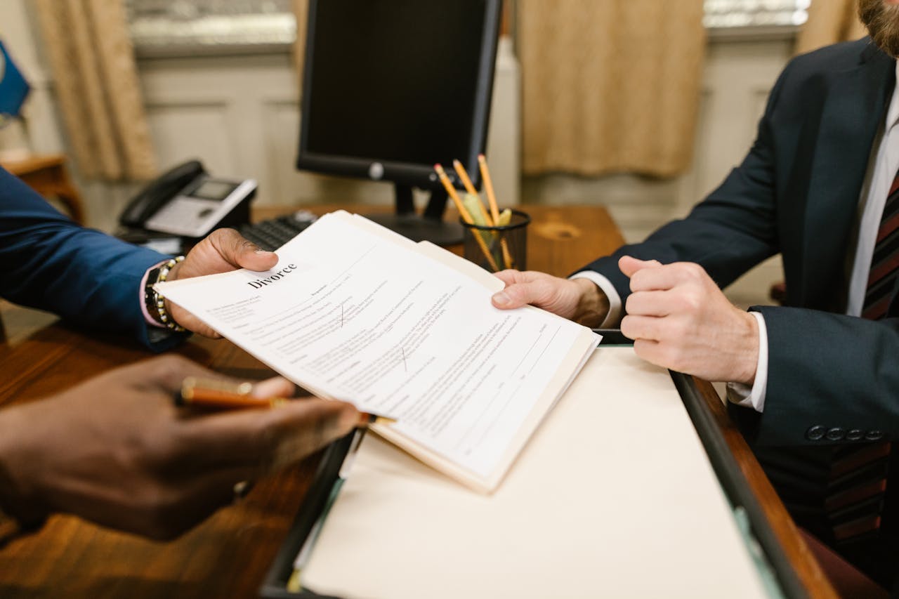 Close-up of hands exchanging divorce documents during legal proceedings in office.